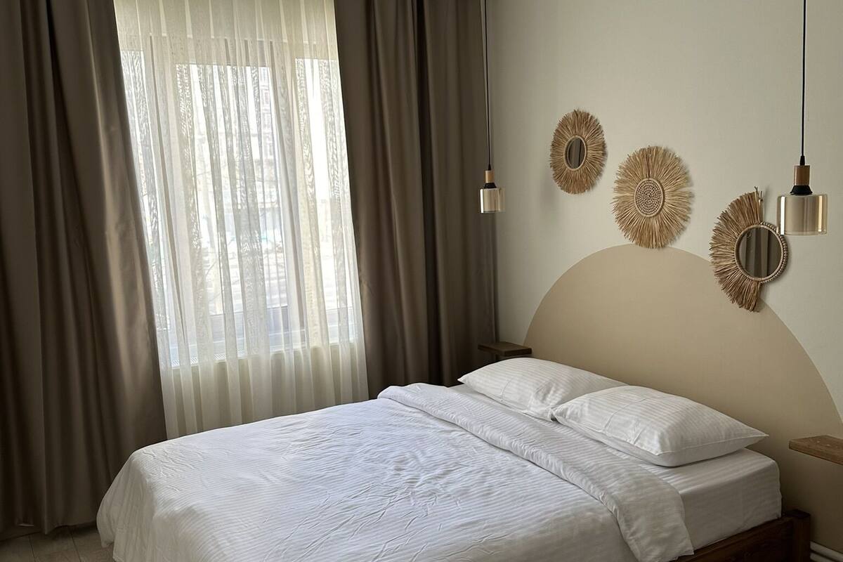 A bedroom with a bed, curtains, a window, and wall decor.