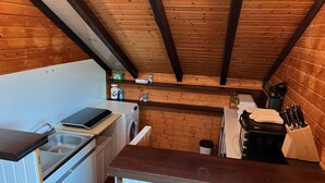Ett litet kök med tvättmaskin, diskho och spis.