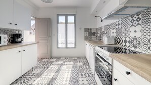 Een moderne keuken met patroontegels, witte kasten en een houten aanrecht.