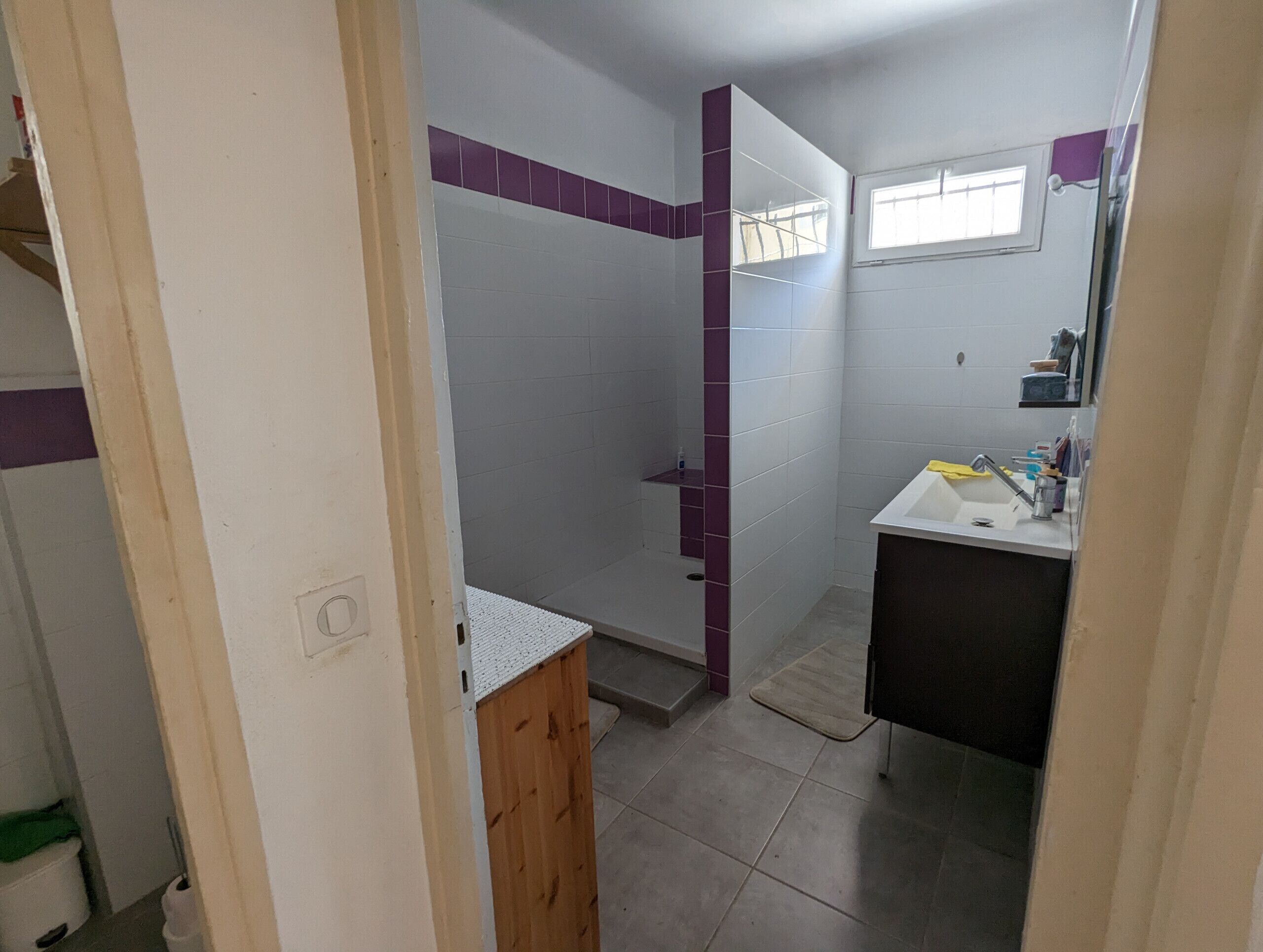 Een badkamer met een douche, wastafel en spiegel.