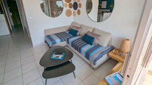 A modern living room with a sofa, a coffee table, and a side table. There are two round mirrors on the wall and a variety of woven wall art.
