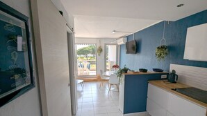 A modern kitchen with white cabinets, a blue accent wall, and a dining area with a table and chairs.
