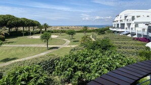 A view of a resort with a pool, a well-maintained lawn, and a building with a curved roof.