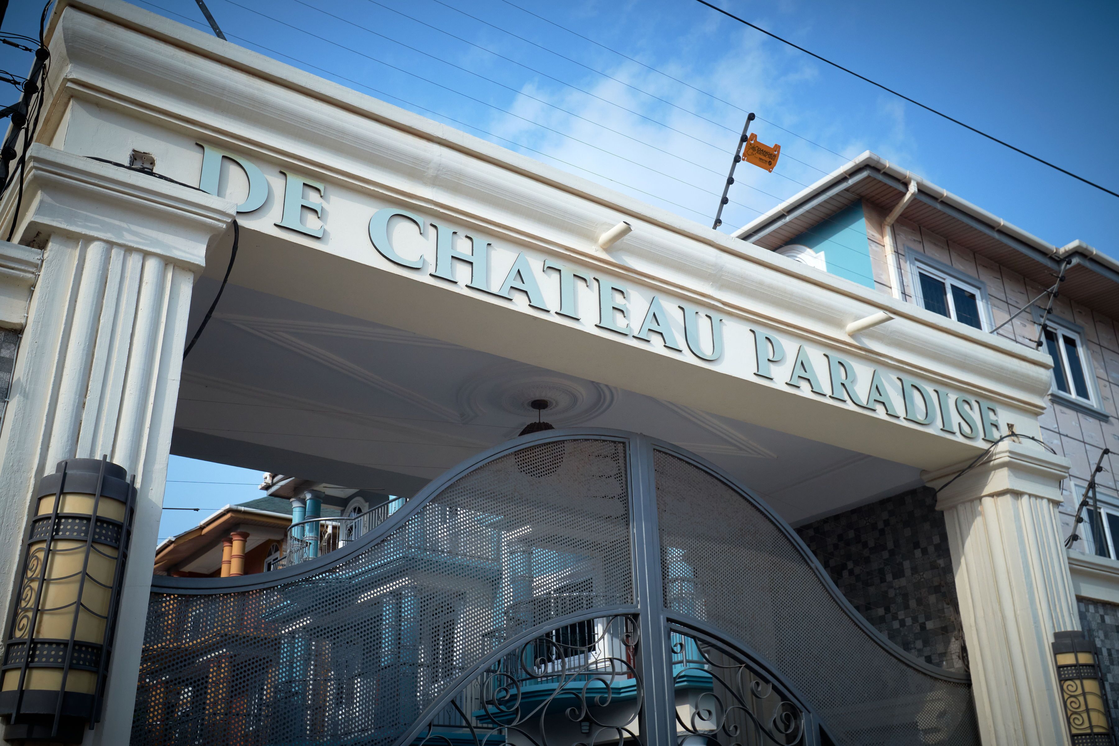 The entrance of Chateau Paradis with a prominent sign and a metal staircase.