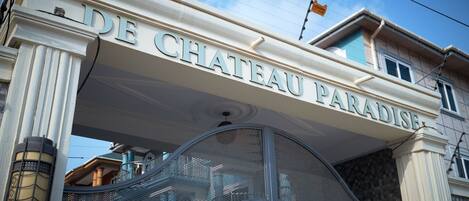The entrance of Chateau Paradis with a prominent sign and a metal staircase.