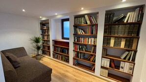 A reading room with multiple bookshelves, a sofa, and a potted plant. - Fachwerkhaus zum Hirsch in Mömbris (Mömbris)