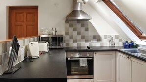 A modern kitchen with a built-in oven, microwave, and coffee maker. - A cosy one-bedroom first floor apartment on Rodborough Common. (Rodborough Common, near Stroud)