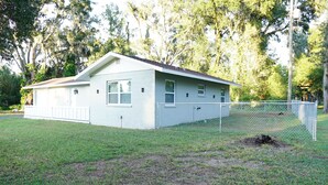 A single-story house with a fenced yard, surrounded by trees. - Spacious Home with Luxury Finish (Brandon)