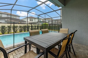 Un patio cubierto con piscina, una mesa y sillas.