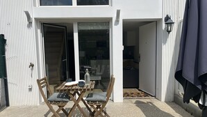 Un área de estar exterior moderna con una mesa y sillas, una botella y una taza sobre la mesa.