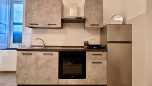A modern kitchen with a built-in oven, a stainless steel refrigerator, and a window with a view of the outdoors. - Donna Rebecca, apartment in fine building with garden (Meta)