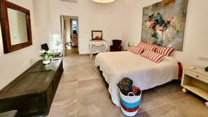 A bedroom with a large bed, a dresser, a desk, a chair, a hanging lamp, and a painting on the wall. - Donna Rebecca, apartment in fine building with garden (Meta)