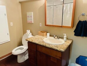A bathroom with a toilet, sink, and mirror. There is a sign above the sink that says "WASH BRUSH FLOSS FLUSH". - Spacious, stocked 1 BR Suite with Yard in Edmonds! (Edmonds)