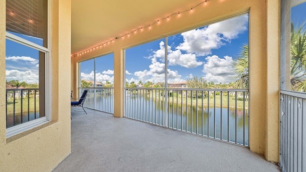A covered outdoor area with large windows, a concrete floor, and a metal railing. - 3/2.5 lakefront condo with 2-car garage in gated community, close to beaches  (Fort Myers)