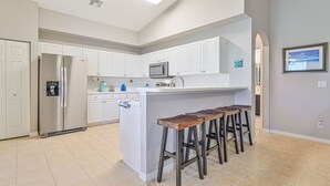 A modern kitchen with white cabinets, stainless steel appliances, and a central island with bar stools. - 3/2.5 lakefront condo with 2-car garage in gated community, close to beaches  (Fort Myers)