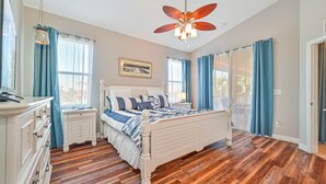 A bedroom with a wooden floor, a white bed, a nightstand, a dresser, and a ceiling fan. - 3/2.5 lakefront condo with 2-car garage in gated community, close to beaches  (Fort Myers)
