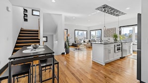 Una cocina moderna con una isla central, suelo de madera y grandes ventanales que ofrecen vistas a la ciudad.