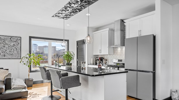 Una cocina moderna con una isla central, armarios blancos y electrodomésticos de acero inoxidable.