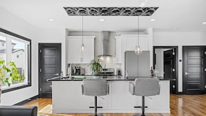 Una cocina moderna con dos taburetes de bar, una isla central e iluminación colgante.