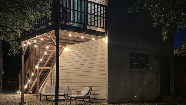 A two-story house with a balcony, outdoor seating, and string lights. - Native Sun - Free Boat/Trailer parking (Medicine Park)