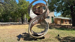 A circular stone sculpture in a grassy area with trees and a building in the background. - Native Sun - Free Boat/Trailer parking (Medicine Park)