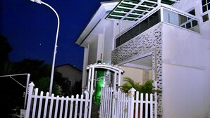 A gated entrance to a building with a white picket fence, a street lamp, and a small garden area with plants. - Viola Apartments & Suites (Abuja)