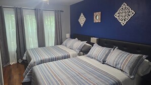 Un dormitorio con dos camas, ventilador de techo y decoración mural.