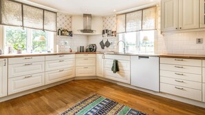 A modern kitchen with white cabinetry, wooden countertops, and a herringbone-patterned backsplash.