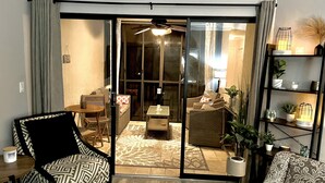 A living room with a sofa, armchair, and a dining area with a table and chairs.
