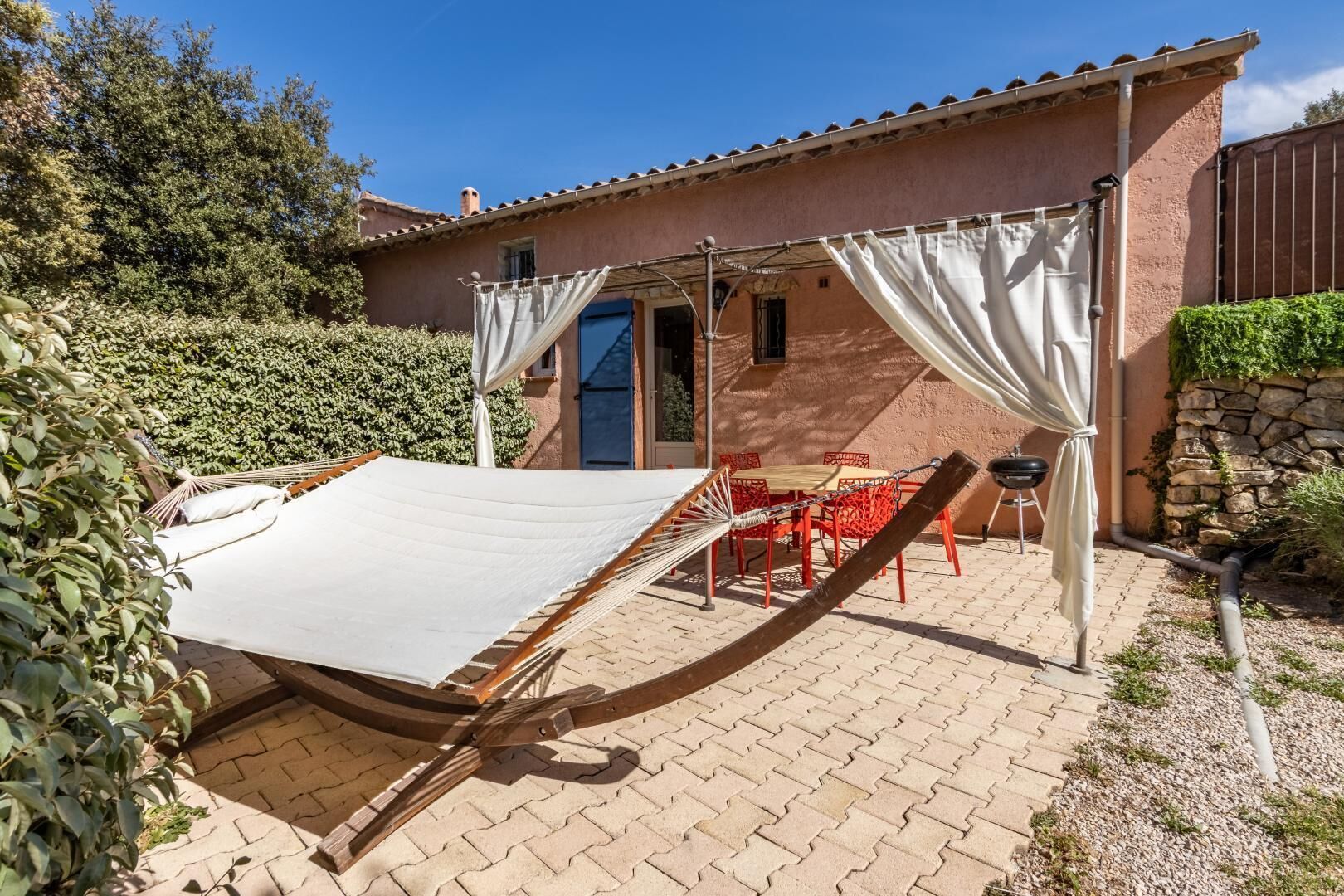 A patio with a hammock, a table, and chairs.