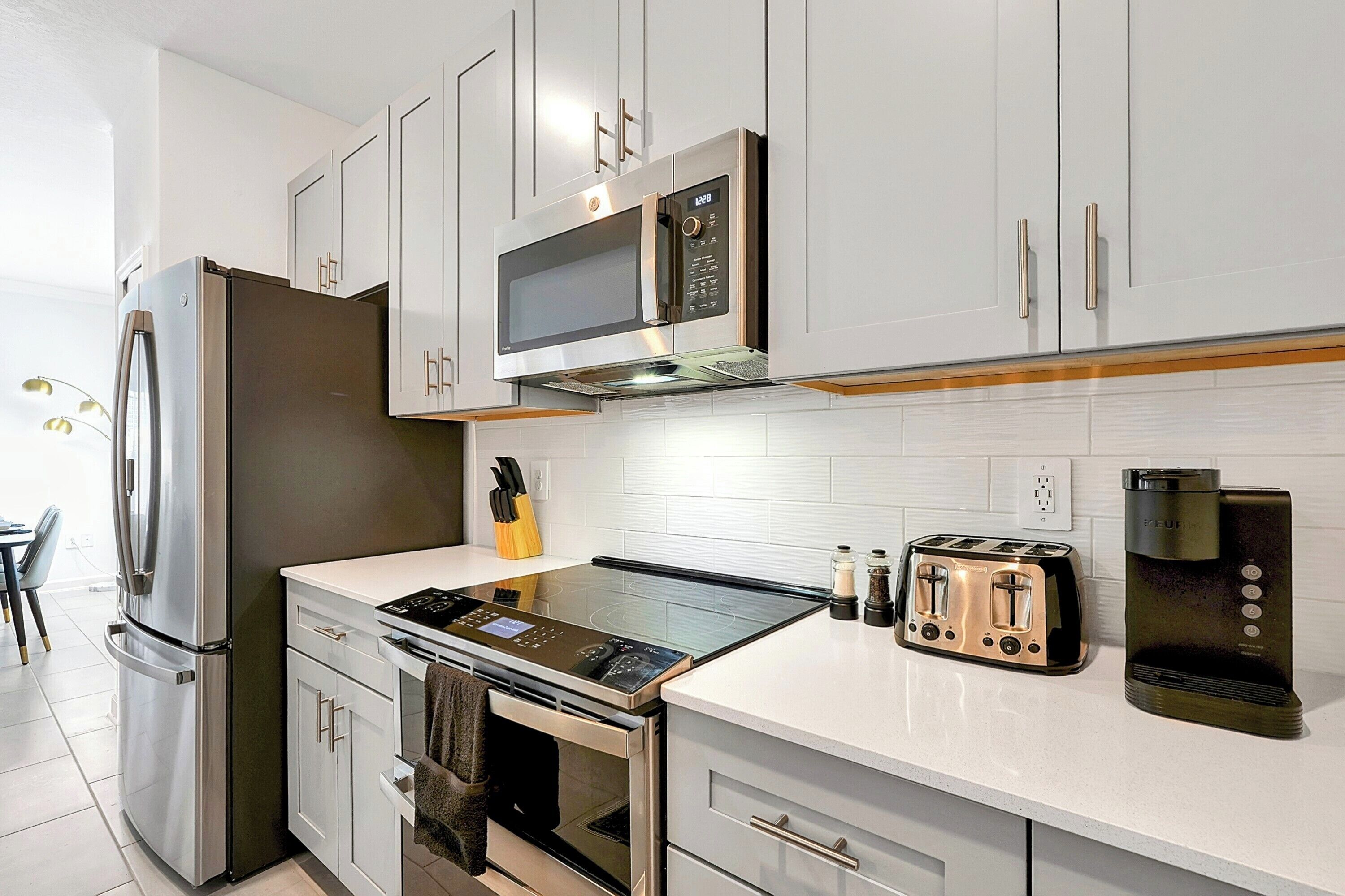 A modern kitchen with stainless steel appliances, a built-in microwave, a toaster, and a coffee maker.