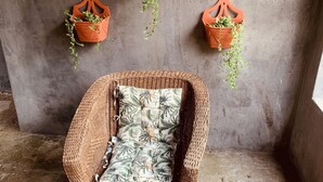 Une chaise en osier avec un coussin à motifs, placée dans un coin.