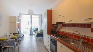 A compact kitchen with a dining area, a view to the outside, and a small living space. - Cozy apartment in Isca Marina with WiFi (Isca Marina)