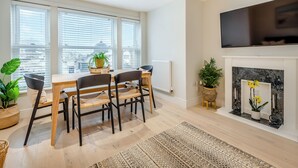 Una sala de estar moderna con comedor, ventanas amplias, chimenea y televisor de pantalla plana montado arriba.