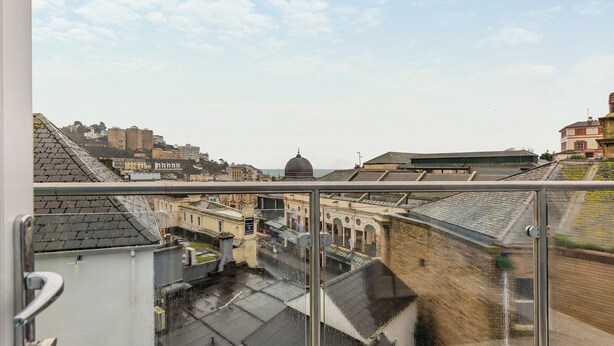 Vista desde un balcón con vistas a un paisaje urbano que incluye edificios históricos, una estructura en forma de cúpula y un río.
