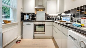 Una cocina moderna con armarios blancos, lavavajillas, horno y cafetera.