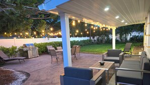 Eine Terrasse im Freien mit Sitzgelegenheiten, einem Grill und Lichterketten.
