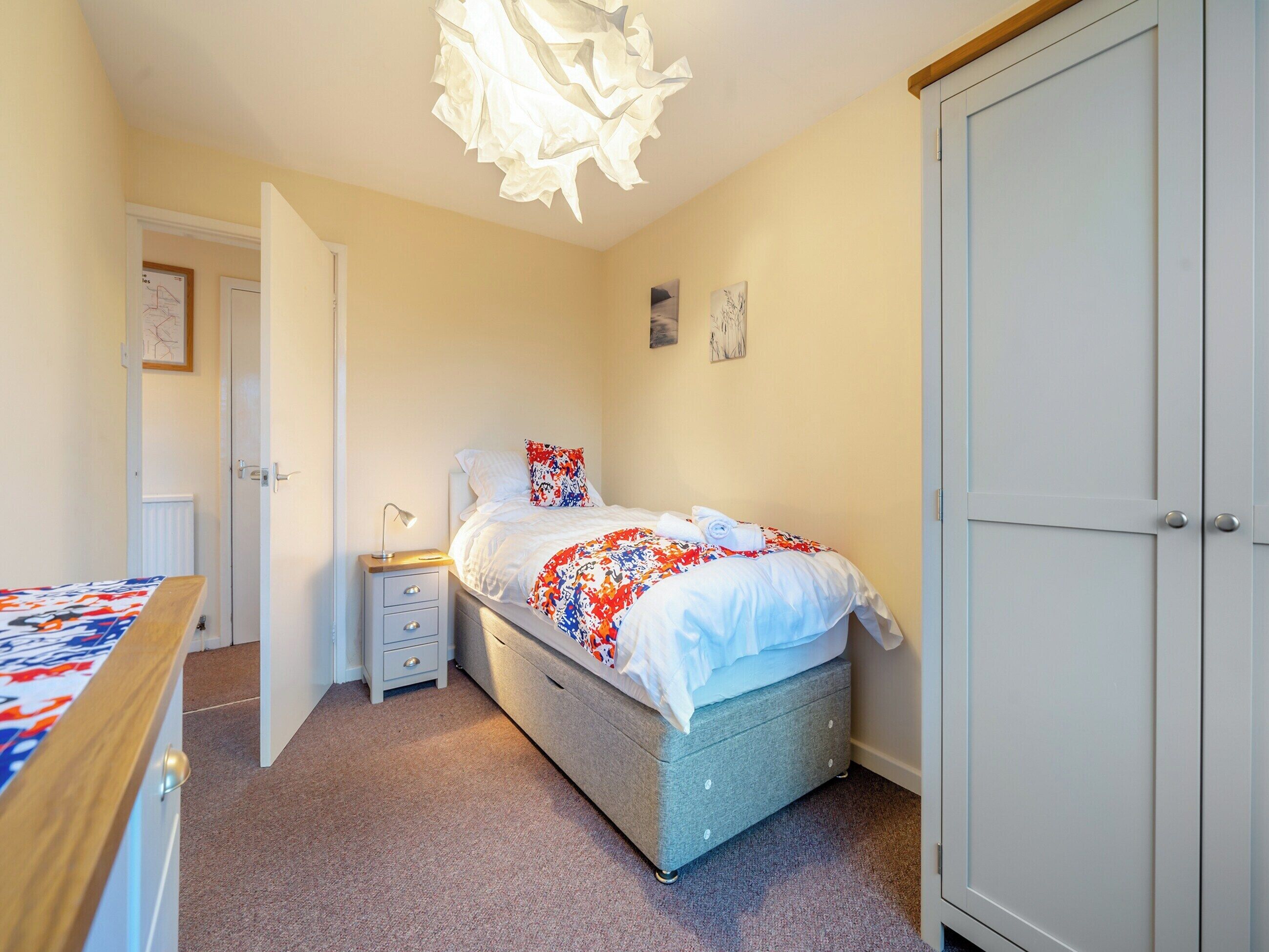 A bedroom with a bed, bedside table, and wardrobe.