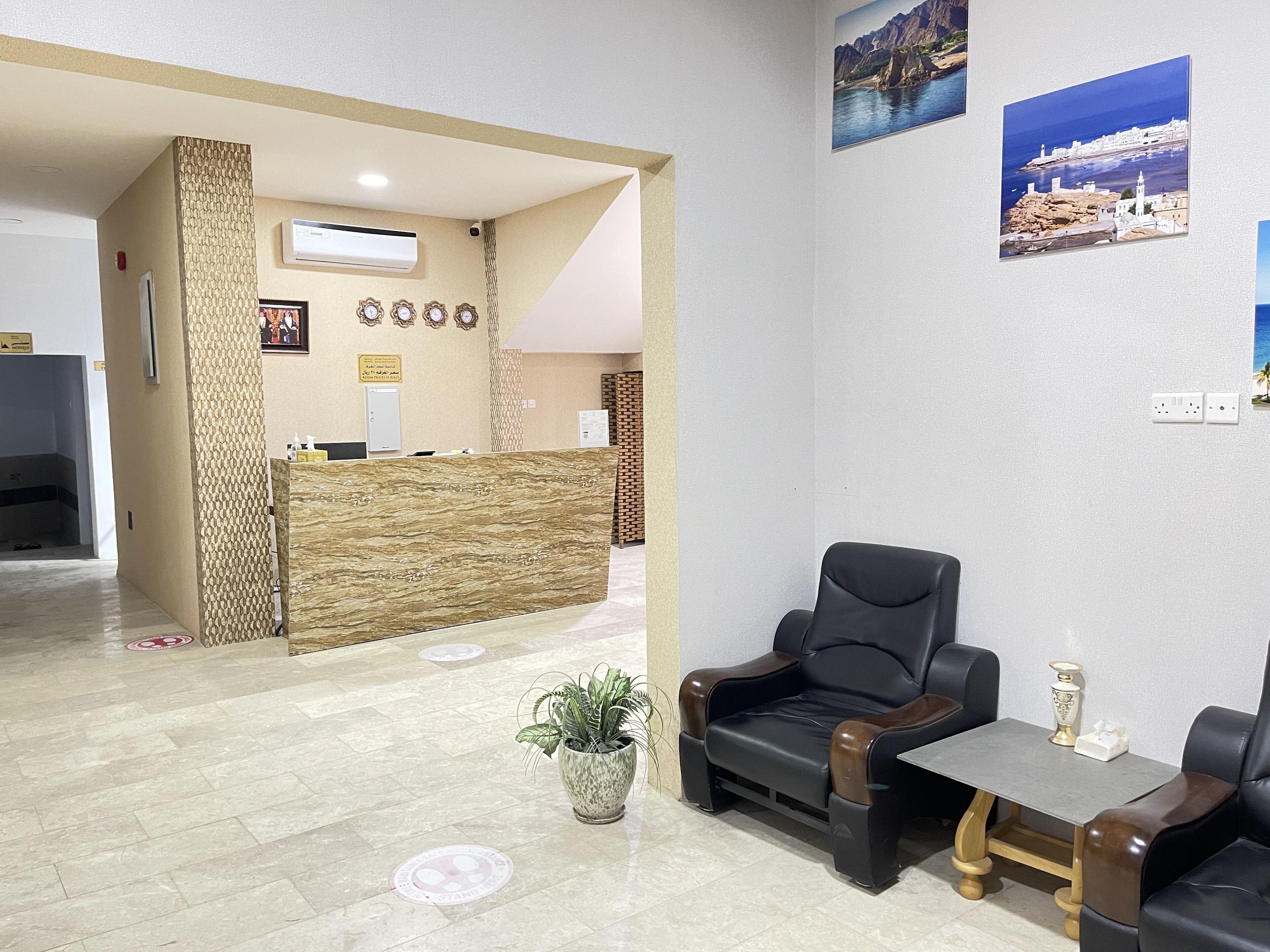A reception area with a reception desk, a black leather sofa, a small table, and a potted plant.