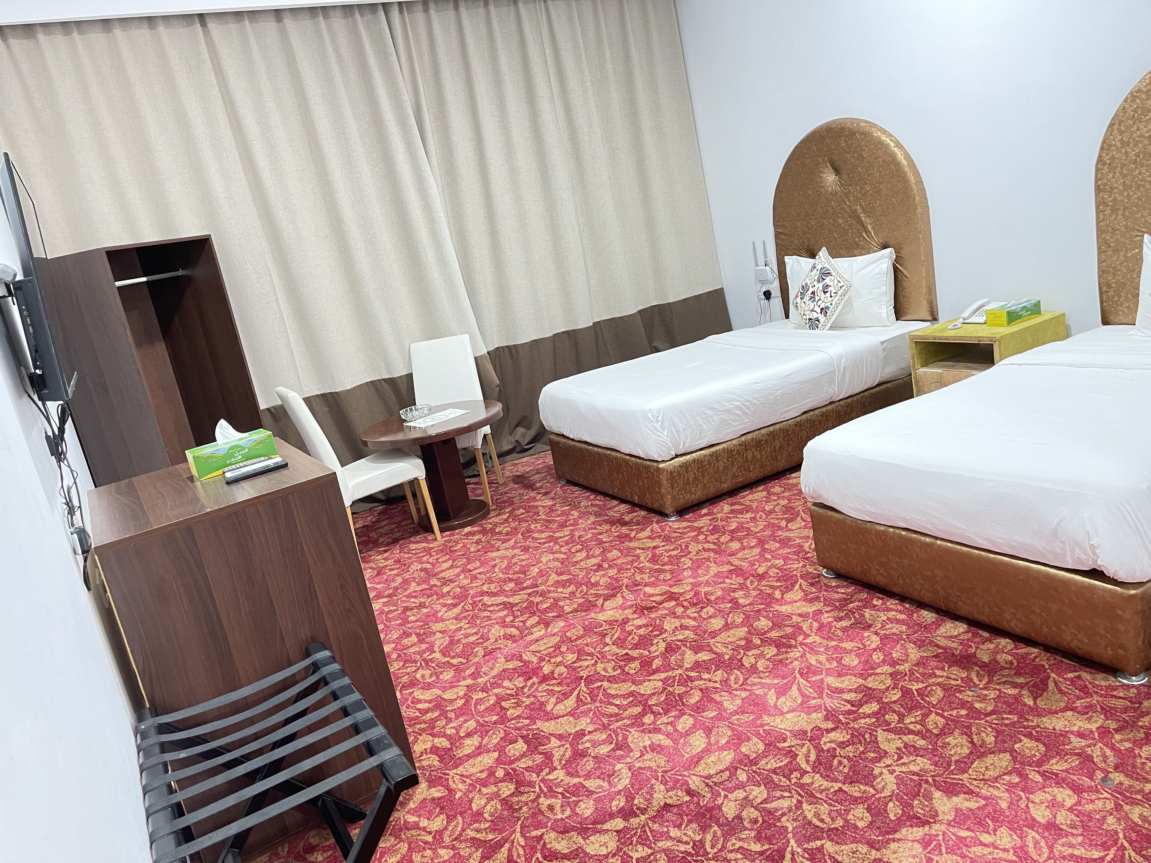 A hotel room with two beds, a desk with a chair, a TV, and a telephone.