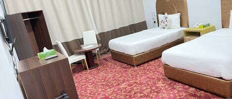 A hotel room with two beds, a desk with a chair, a TV, and a telephone.
