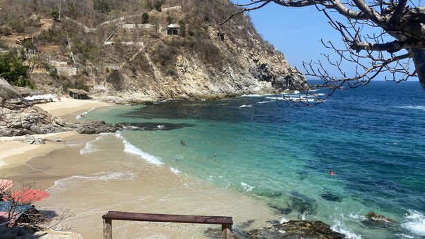 A beach with clear turquoise water, rocky cliffs, and a few people swimming. - 3 Bedroom Villa with Rooftop Plunge Pool, Starlink Wi-Fi (San Pedro Pochutla)