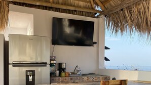 A kitchen with a TV, refrigerator, and bar stools. - 3 Bedroom Villa with Rooftop Plunge Pool, Starlink Wi-Fi (San Pedro Pochutla)