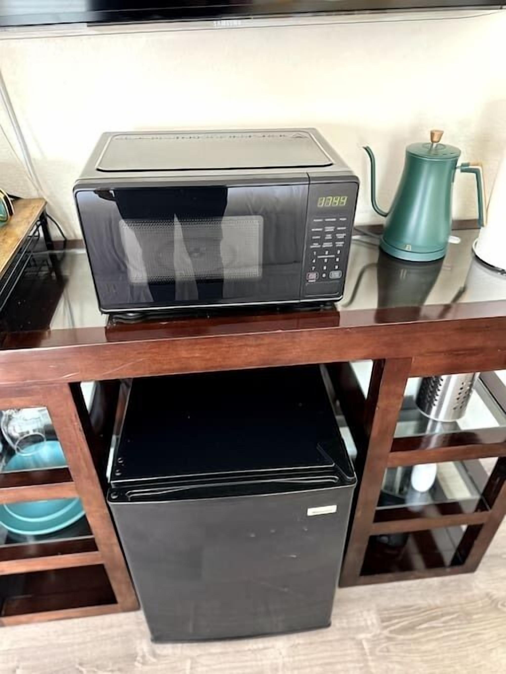 Une cuisine équipée d’un four à micro-ondes et d’un réfrigérateur noir.