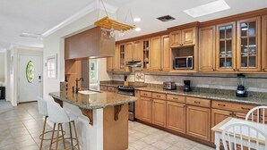 Una cocina con armarios de madera, encimera de granito y microondas integrado.