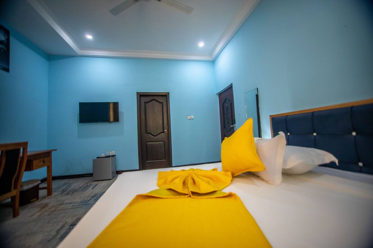 Une chambre d’hôtel avec un lit, une télévision, une porte et une petite table.