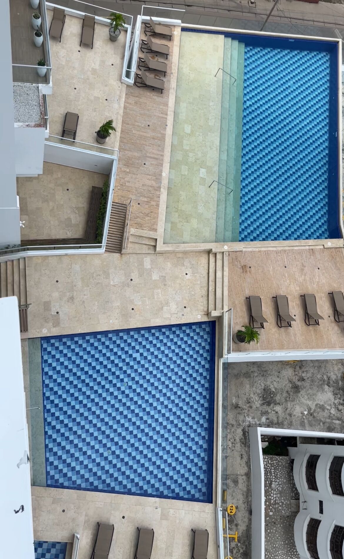 A rooftop pool area with multiple lounge chairs and a checkered pool floor.