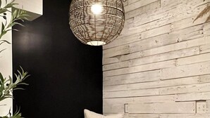 Quarto com cama, uma cadeira, luminária pendente e parede com design em painéis de madeira.
