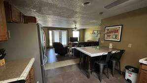 A kitchen with a refrigerator, stove, and dining area with chairs and a table.