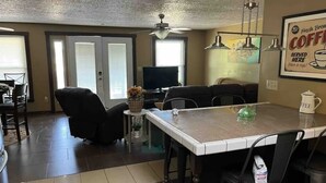A dining area with a table, chairs, a television, and a coffee mug on the wall.